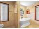 Elegant bathroom with a soaking tub, marble tiles, and a decorative window niche at 585 Summerhaven Dr, Debary, FL 32713