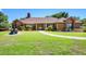 Charming brick home with manicured lawn, garden features, and walkway leading to a bright yellow front door at 585 Summerhaven Dr, Debary, FL 32713