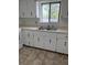 Close up of a condo kitchen featuring neutral countertops, stainless steel sink, and white cabinets at 600 N Boundary Ave # 114-C, Deland, FL 32720