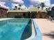 Community pool surrounded by palm trees, blue skies, and a covered seating area at 600 N Boundary Ave # 114-C, Deland, FL 32720