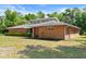 Brick home on a large lawn featuring modern details such as clerestory windows and a well maintained yard at 6185 Shoreline Dr, Port Orange, FL 32127