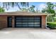 Sleek garage door with glass panels, complementing the brick exterior and modern design with adjacent entryway door at 6185 Shoreline Dr, Port Orange, FL 32127