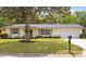 A well-manicured lawn and mature tree enhance the curb appeal of this charming single-story home at 736 Lindenwood W Cir, Ormond Beach, FL 32174