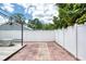 A well-maintained backyard featuring a brick patio, white privacy fence, and mature trees at 952 Northbrook Dr, Ormond Beach, FL 32174