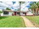 Inviting single-story home with a well-kept lawn, complemented by a vibrant red door and manicured landscaping at 952 Northbrook Dr, Ormond Beach, FL 32174