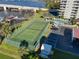 Aerial view of a tennis court next to condos, a pool, and covered parking at 100 Silver Beach Ave # 608, Daytona Beach, FL 32118