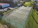 Aerial view of a green tennis court surrounded by palm trees, parking, and grass at 100 Silver Beach Ave # 608, Daytona Beach, FL 32118