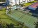 Aerial view of a green tennis court surrounded by palm trees next to a condo and pool at 100 Silver Beach Ave # 608, Daytona Beach, FL 32118