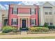 Charming two-story townhome featuring a bright pink facade, black shutters, and manicured landscaping at 103 Manor View Ln, Deland, FL 32724