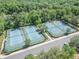 Aerial view of well-maintained tennis courts surrounded by lush greenery, offering a perfect recreational space at 103 Manor View Ln, Deland, FL 32724
