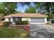 Charming home featuring a manicured front yard, a screened entry, and a two-car garage at 1057 Shady Hollow Dr, Deland, FL 32724