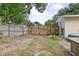 Fenced back yard with gravel, grass, and a wooden gate provides privacy and security at 1090 Wakefield Cir, Deltona, FL 32725