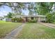 Charming single-story home featuring a lush front yard, covered parking, and mature landscaping at 1090 Wakefield Cir, Deltona, FL 32725