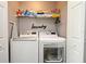 This laundry room features a front-load washer and dryer, a storage shelf, and a laundry sign at 116 Neal Dr, Deltona, FL 32738