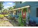 Red front door with dolphin decor and well-manicured landscaping on a charming blue home at 1228 Oakwood Ave, Daytona Beach, FL 32114