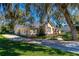 Stunning exterior view of the home with a long driveway, mature trees, and lush landscaping at 1309 Wicklow Ln, Ormond Beach, FL 32174