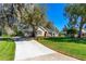 Beautiful home exterior with a well-manicured lawn, mature trees, and a long driveway at 1309 Wicklow Ln, Ormond Beach, FL 32174