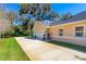 Beige home showing three-car garage, well-maintained lawn, and a long driveway, surrounded by lush landscaping at 1309 Wicklow Ln, Ormond Beach, FL 32174