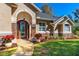 Charming home exterior featuring a stone accent, arched door and manicured front yard with vivid red poinsettias at 1309 Wicklow Ln, Ormond Beach, FL 32174