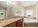 Bright bathroom featuring granite counters, a soaking tub, and a large mirror at 1481 Areca Palm Dr, Port Orange, FL 32128