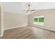 Bright bedroom with wood-look floors, a ceiling fan, and a large window overlooking the front yard at 1481 Areca Palm Dr, Port Orange, FL 32128