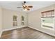 Well-lit bedroom with wood-look floors, a ceiling fan, and three windows with blinds at 1481 Areca Palm Dr, Port Orange, FL 32128