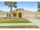 Charming, beige single-story home with a two car garage, complemented by a lush lawn and mature palm tree at 1481 Areca Palm Dr, Port Orange, FL 32128