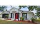 Charming single-story home with red door, black trim, fresh landscaping, and black two-car garage door at 1568 Pendleton St, Deltona, FL 32725