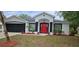 Charming single-story home with red door, black trim, fresh landscaping, and black two-car garage door at 1568 Pendleton St, Deltona, FL 32725