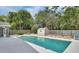Backyard pool with adjacent storage shed and privacy fence surrounded by mature trees for shade and seclusion at 1590 Urbana Ave, Deltona, FL 32725