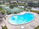 Aerial view shows a community pool and tennis court near a tranquil pond, fringed by palm trees at 16 Big Buck Trl, Ormond Beach, FL 32174
