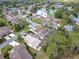 An aerial shot featuring residences near a pond and tennis court surrounded by green trees at 16 Big Buck Trl, Ormond Beach, FL 32174