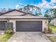 Exterior view of a townhome with a wide garage, number 16, a manicured lawn, and stone accents at 16 Big Buck Trl, Ormond Beach, FL 32174