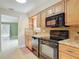 Kitchen with wood cabinets, granite countertops, and black appliances at 16 Big Buck Trl, Ormond Beach, FL 32174