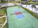 Aerial view of a well-kept tennis court next to a pond, bordered by trees and palm trees at 16 Big Buck Trl, Ormond Beach, FL 32174