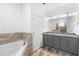 Bathroom with a double sink vanity, granite countertops, tub, and elegant tile at 1626 Lansfield Ave, Deltona, FL 32738