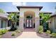Elegant home entrance featuring a double door, stone pillars and brick walkway lined with tropical plants and lush landscaping at 183 Mcgregor Rd, Deland, FL 32720