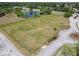 An aerial view of a large grassy field with a pond, road, and trees at 1860 Forough Cir, Port Orange, FL 32128