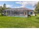 Expansive backyard featuring a screened pool enclosure and well-manicured lawn at 1860 Forough Cir, Port Orange, FL 32128