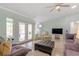 Inviting living room with doors to the lanai, ceiling fan, large windows, and comfortable furnishings at 1862 Shelby Ter, Deltona, FL 32725