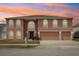 Charming two-story home featuring arched windows, a three-car garage, and lush landscaping against a colorful sunset at 193 Fish Hawk Dr, Winter Haven, FL 33884