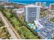 Aerial view features the high-rise condo building next to a lush golf course and ocean at 2 Oceans West Blvd # 1007, Daytona Beach, FL 32118