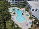 Aerial view of the kidney-shaped community pool with palm trees, lounge chairs, tables and a jacuzzi at 2 Oceans West Blvd # 1007, Daytona Beach, FL 32118