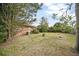 Open backyard view with mature trees, grass, and the home's exterior at 2126 Sabal Palm Dr, Edgewater, FL 32141