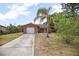 Charming brick home featuring a one-car garage, concrete driveway, and tropical landscaping at 2126 Sabal Palm Dr, Edgewater, FL 32141