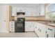 Bright kitchen featuring white cabinets, tile flooring, and modern black appliances at 2126 Sabal Palm Dr, Edgewater, FL 32141
