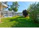 Lush backyard featuring a screened-in pool area, a well-kept lawn, and mature trees at 2213 Needle Palm Dr, Edgewater, FL 32141