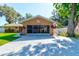 Charming single-story home featuring an orange facade, screened-in garage, and well-maintained landscaping at 2213 Needle Palm Dr, Edgewater, FL 32141
