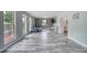 Bright living room featuring gray wood-look flooring, large windows, and a brick accent wall at 2254 Green St, South Daytona, FL 32119