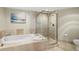 An elegant bathroom featuring a soaking tub with marble surround, glass shower and modern fixtures at 231 Riverside Dr # 2310, Holly Hill, FL 32117
